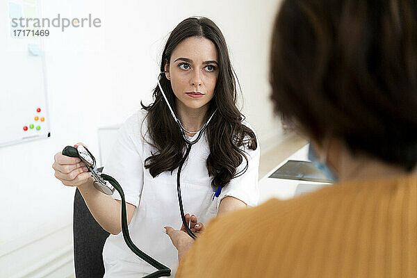 Schöne Ärztin  die den Blutdruck eines Patienten in einer Klinik kontrolliert