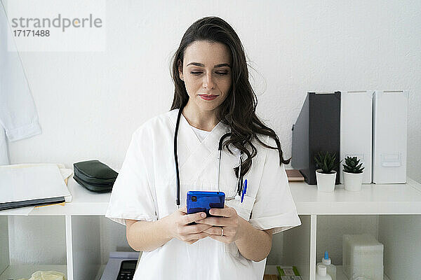 Ärztin  die in der Klinik eine Textnachricht auf ihrem Smartphone schreibt