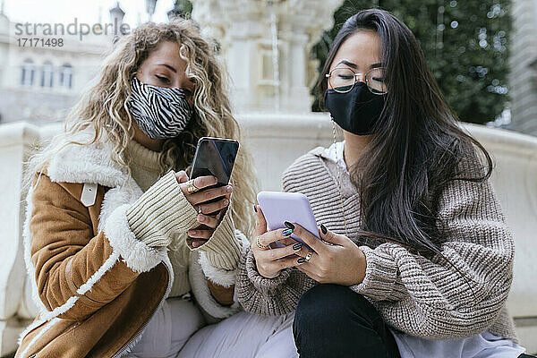 Multi-ethnic women using smart phone wearing protective face mask during pandemic