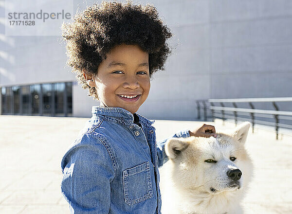 Lächelnder Junge spielt mit Hund im Freien