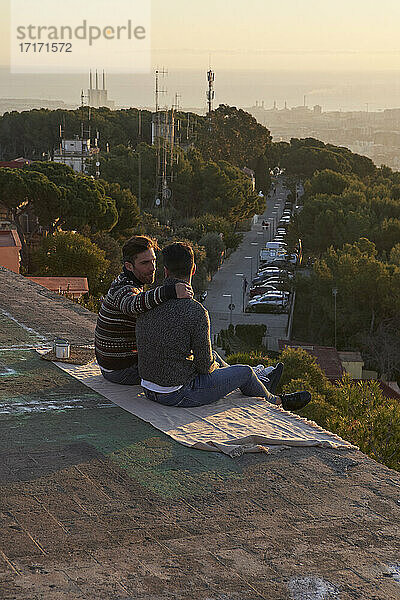 Schwule Freunde unterhalten sich während des Sonnenaufgangs auf dem Aussichtspunkt  Bunkers del Carmel  Barcelona  Spanien