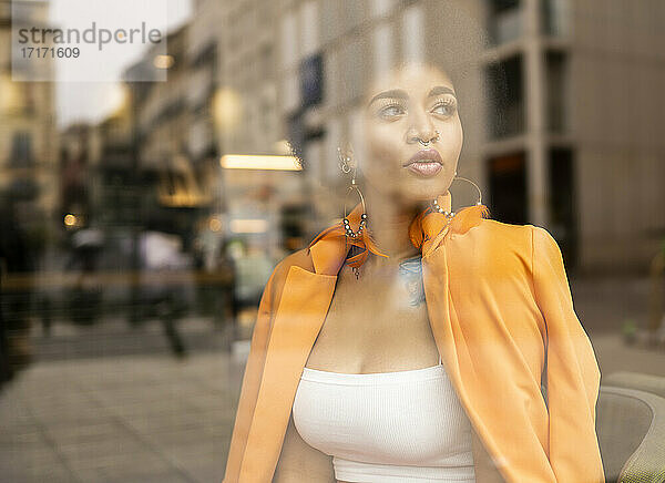 Thoughtful woman looking through glass at cafe