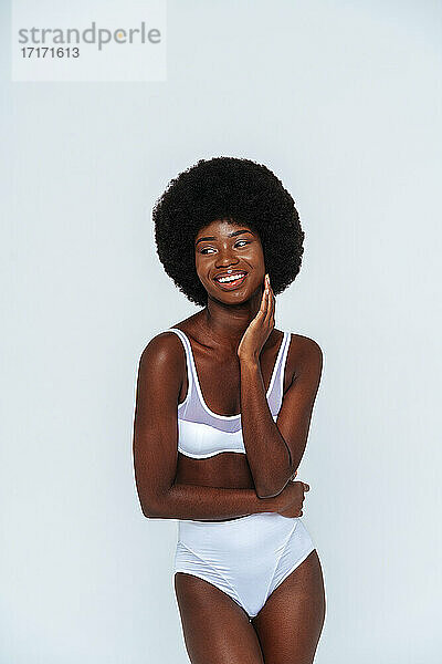 Skinny afro junge Frau trägt Dessous Blick weg  während posiert gegen weißen Hintergrund