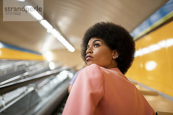 Afro woman on escalator at subway station