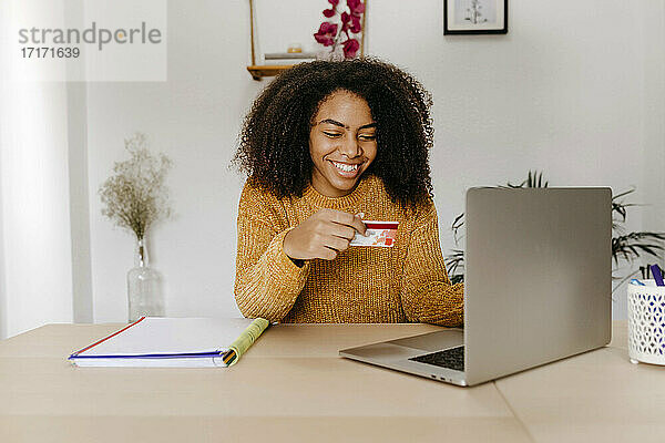 Junge Frau mit Kreditkarte  die einen Laptop benutzt  während sie zu Hause im Büro sitzt