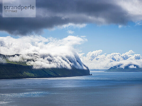Idyllic view of Vagar island by sea against cloudy sky  Iceland