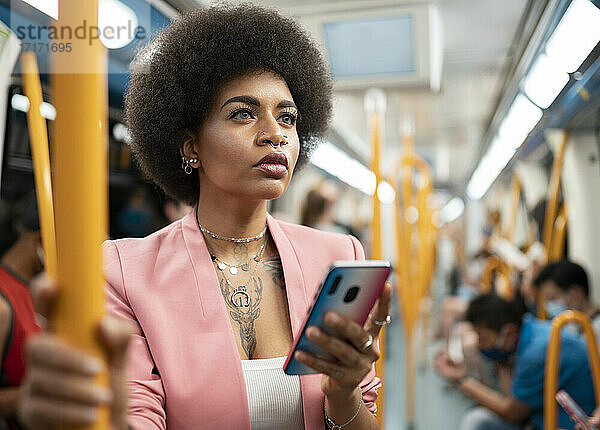 Afro woman with smart phone in train