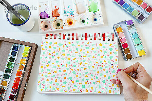 Painting pastel colors terrazzo pattern with watercolors on spiral notebook