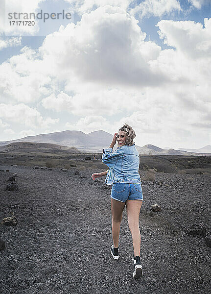 Junger Tourist lächelt beim Spaziergang auf dem Fußweg am Vulkan El Cuervo  Lanzarote  Spanien