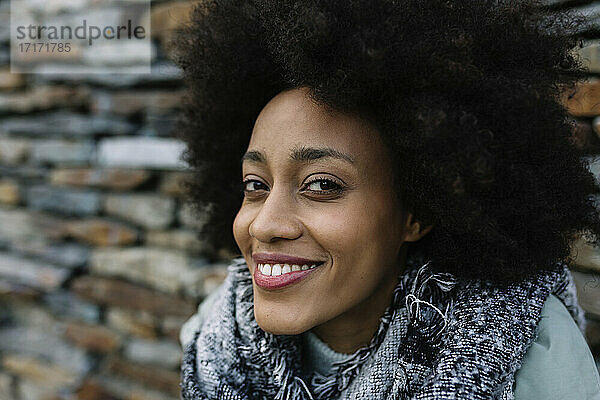 Lächelnde Afro-Frau vor Steinmauer