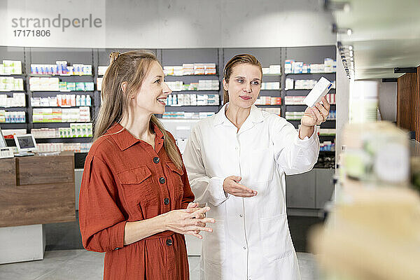 Female pharmacist assisting woman with prescription at store