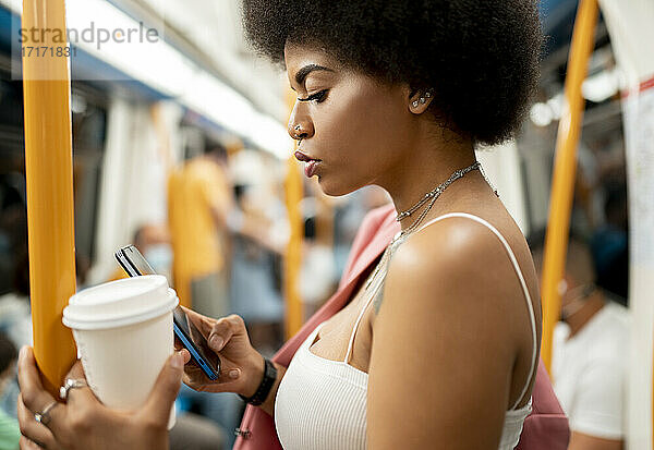 Young woman text messaging on mobile phone in train
