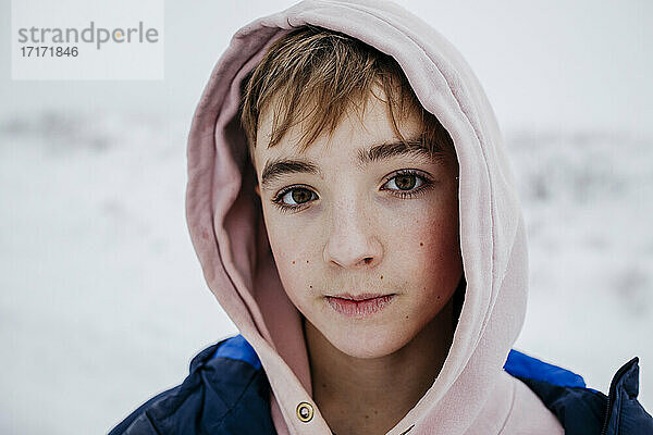 Jugendlicher mit braunen Augen in warmer Kleidung im Schnee
