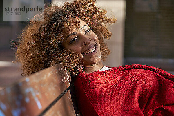 Young woman smiling while leaning on bench