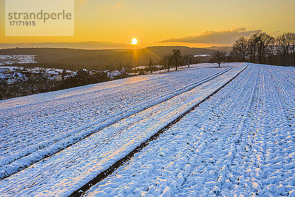 Drohnenansicht eines schneebedeckten Feldes bei Wintersonnenuntergang