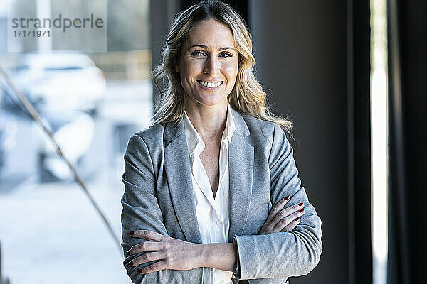 Confident businesswoman smiling while standing at office