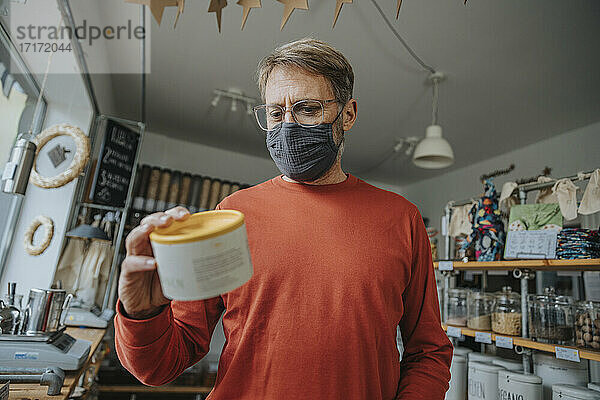 Älterer Mann prüft das Etikett eines Lebensmittelbehälters in einem Zero-Waste-Shop während einer Pandemie