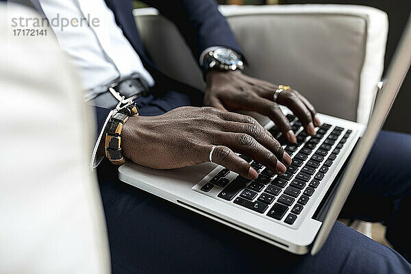 Junger Geschäftsmann  der einen Laptop benutzt  während er im Hotel sitzt