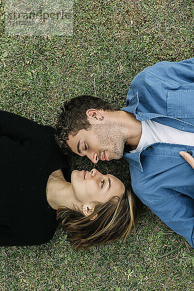 Lächelndes Paar auf dem Rasen liegend