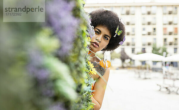 Young woman hiding behind plant