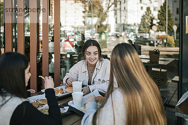 Weibliche Freunde unterhalten sich bei einem schnellen Essen in einem Restaurant im Freien