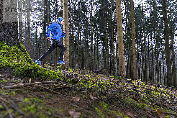Männlicher Jogger beim Laufen im winterlichen Nadelwald