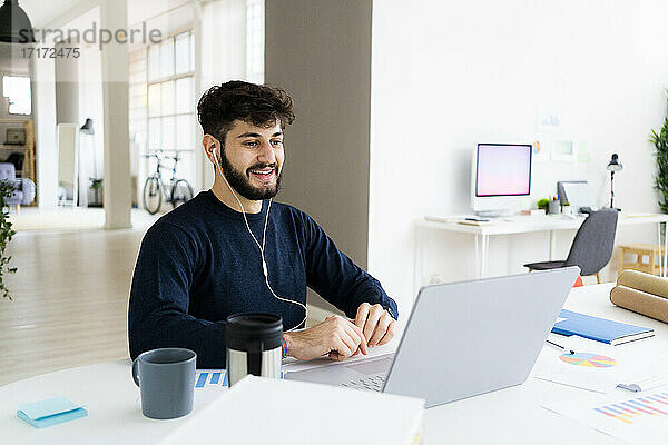 Junger Geschäftsmann mit Videoanruf über Laptop im Kreativbüro
