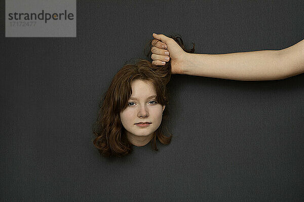Studio shot of male hand holding hair of teenage girl