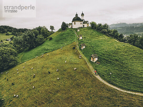 Luftaufnahme einer Frau  die auf einem grünen Hügel in Richtung Kapelle geht  gegen den Himmel
