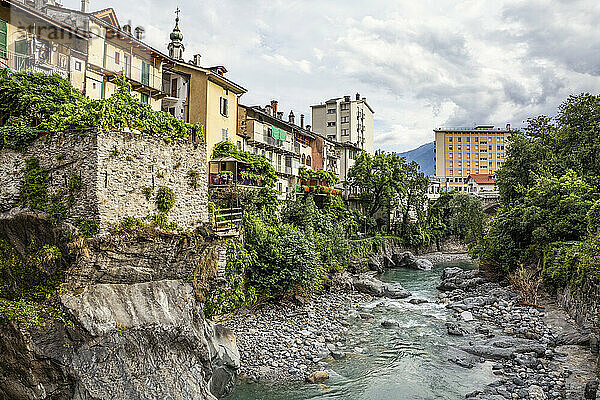 Der Fluss Mera fließt durch die Felsen zwischen den Gebäuden der Stadt gegen den Himmel  Valchiavenna  Chiavenna  Provinz Sondrio  Lombardei  Italien