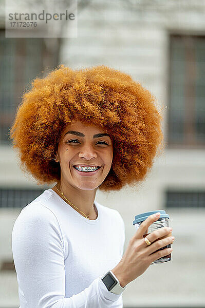 Smiling woman drinking coffee while standing outdoors