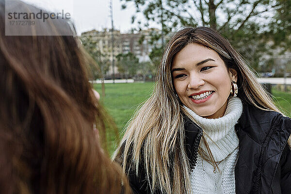 Smiling young woman with female friend at public park