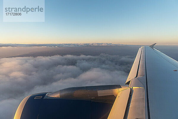 Flügel eines Flugzeugs  das in der Morgendämmerung über Wolken fliegt