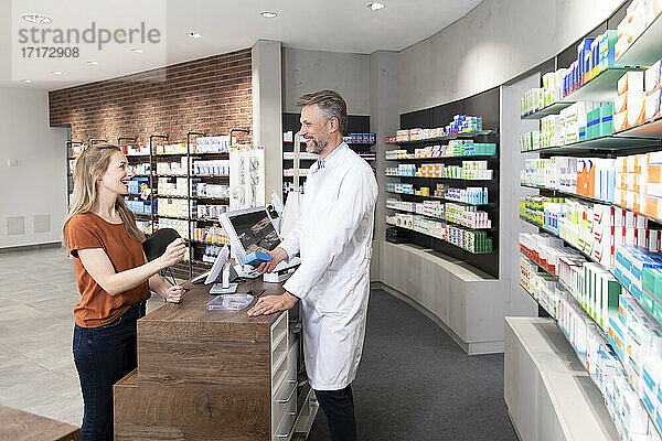 Female customer talking with pharmacist at pharmacy checkout