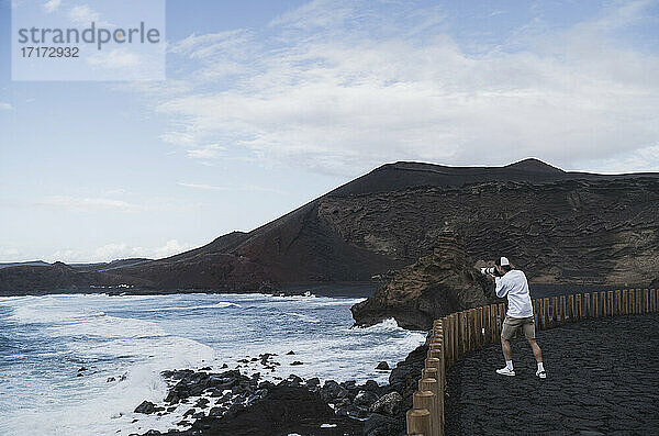 Männlicher Tourist beim Fotografieren vom Aussichtspunkt in El golfo  Lanzarote  Spanien