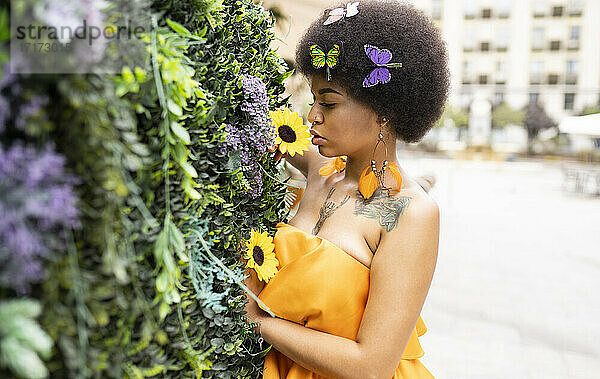 Young female hipster smelling flower outdoors