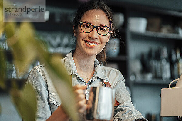 Lächelnde Managerin mit Kaffeekanne in einem Cafe