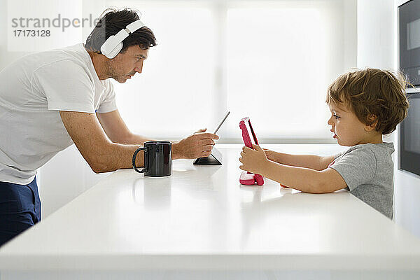 Vater und Sohn verwenden digitale Tablets in der Küche