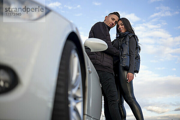 Selbstbewusstes Paar starrt beim Stehen neben dem Auto in den Himmel