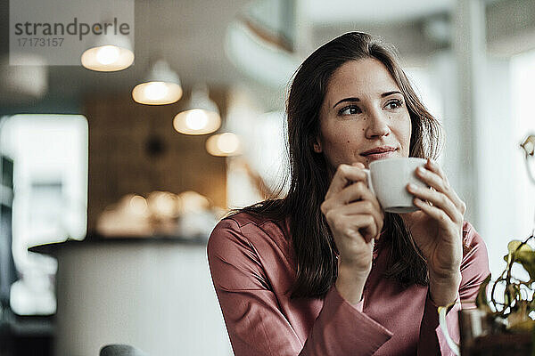 Geschäftsfrau mit Kaffeetasse in der Hand und nachdenklich in einem Cafe