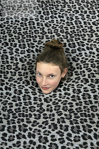 Studio shot of head of teenage girl sticking out of leopard print