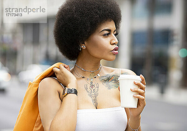 Afro woman with coffee cup outdoors