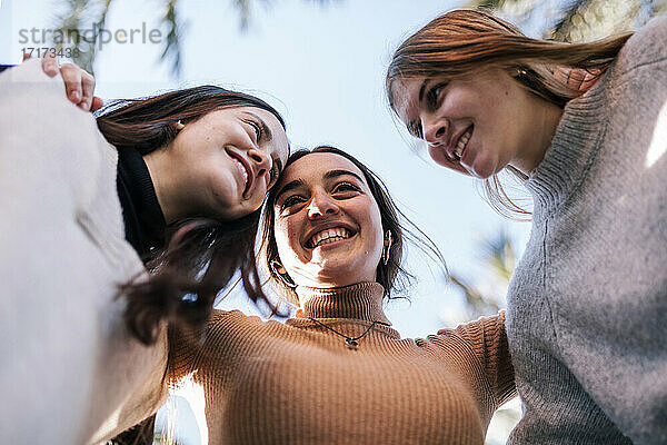 Lächelnde Freundinnen im Teenageralter  die sich im Park an den klaren Himmel kuscheln