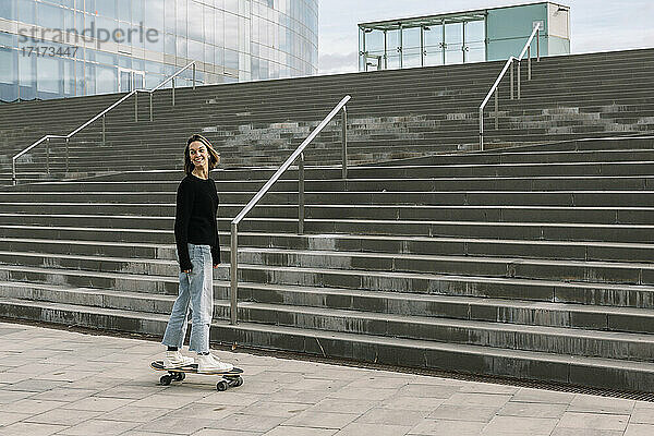 Junge Frau auf dem Skateboard in der Nähe der Treppe