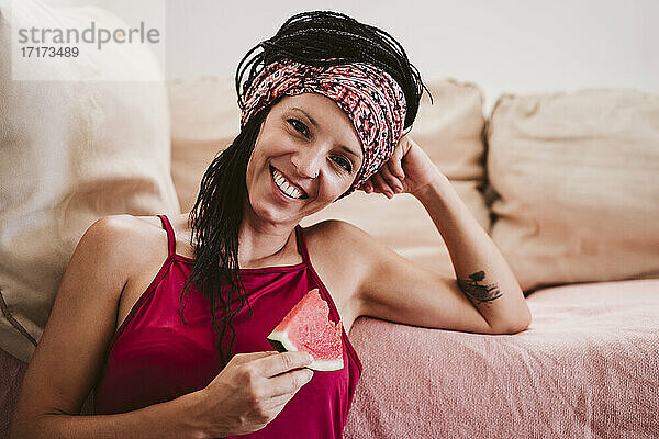 Frau lächelnd beim Essen Wassermelone zu Hause sitzen