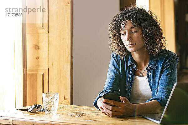 Young female freelancer using smart phone at home office