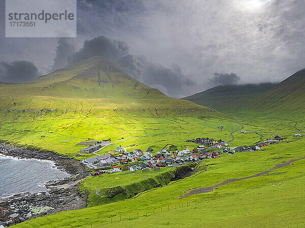 Green landscape and village by sea against cloudy sky  Iceland