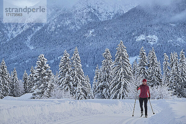 Ältere Frau beim Skifahren mit Skistock auf Schnee über Berg