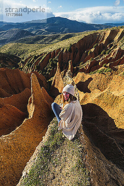 Lächelnde junge Frau auf einer Felsformation sitzend  Valdepenas de la Sierra  Spanien