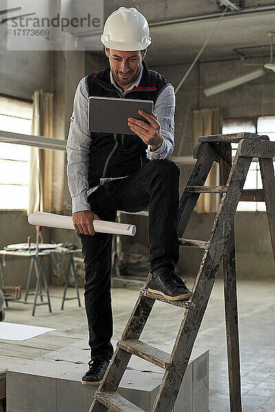 Männlicher Ingenieur  der ein digitales Tablet benutzt  während er in einem Gebäude auf der Baustelle steht
